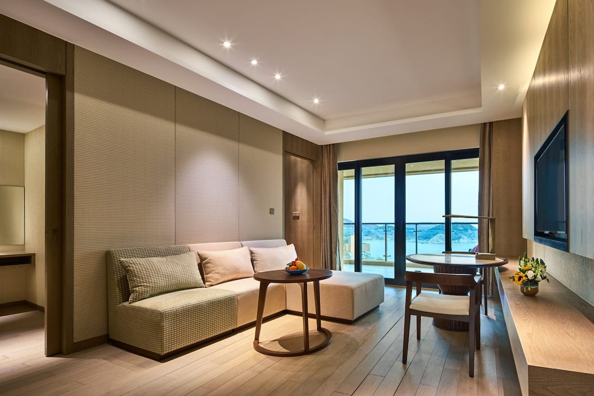 Un salon moderne avec un canapé, une table ronde et une vue sur la mer.