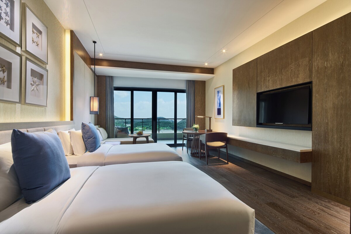 Une chambre d’hôtel avec un grand lit, un téléviseur fixé au mur et un balcon avec vue.