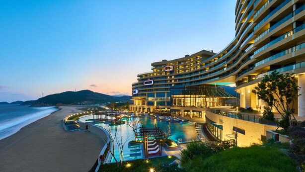Un hôtel doté de nombreux balcons, d’une piscine et offrant une vue sur la plage.
