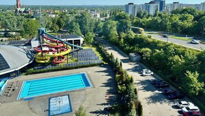 Une piscine, des toboggans aquatiques et un parking avec des voitures.