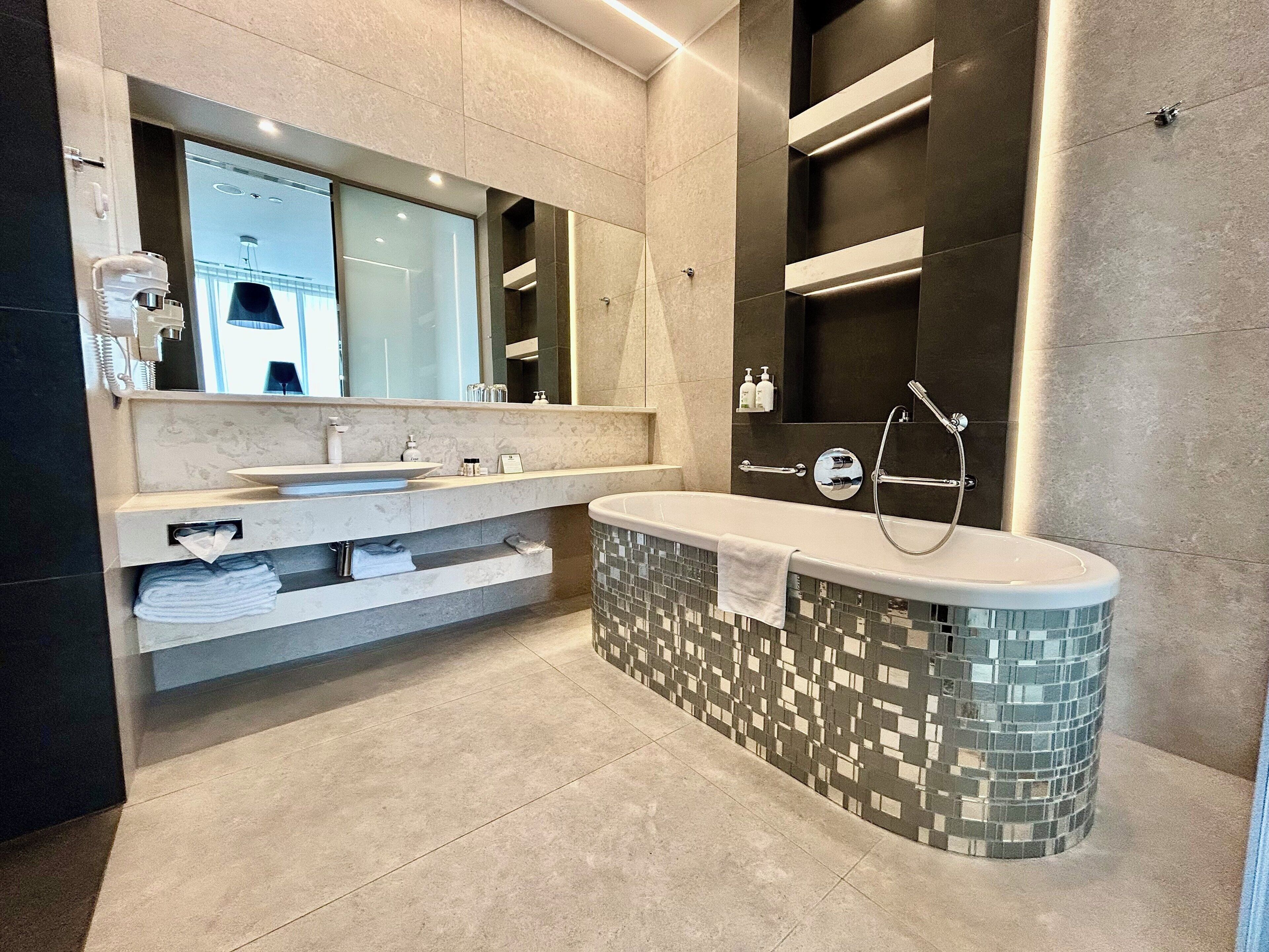 A modern bathroom with a large bathtub, a double sink vanity, and a mirror above the vanity.