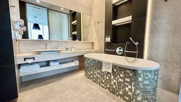A modern bathroom with a large bathtub, a double sink vanity, and a mirror above the vanity.
