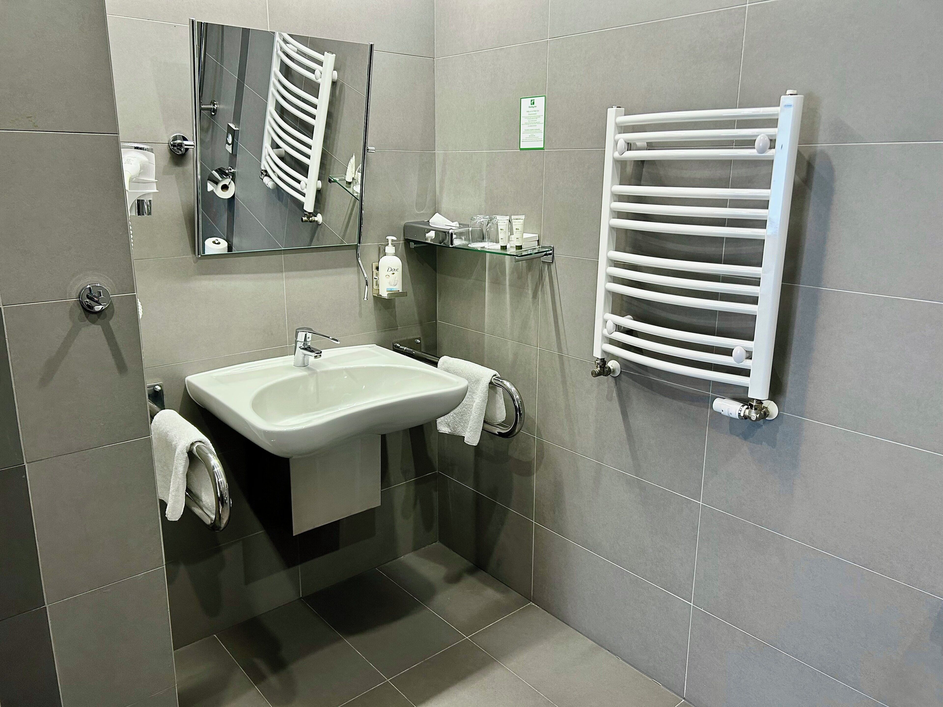 A modern bathroom with a white sink, a glass shower enclosure, and a white towel rack.