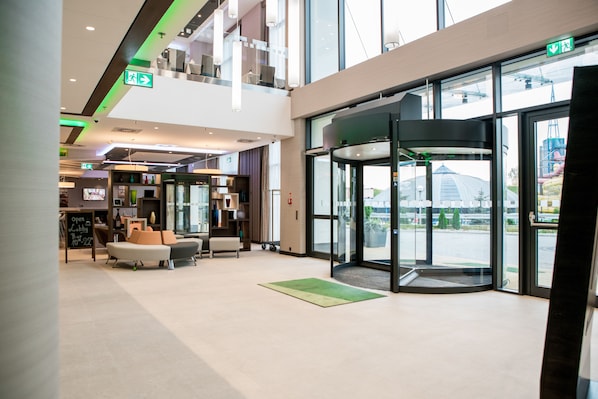 Un hall d’entrée moderne doté d’une porte tournante, d’un espace salon et offrant une vue sur l’extérieur.