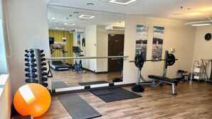 Une salle de sport équipée de matériel d’exercice, d’un miroir et d’un grand ballon orange.