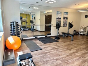 A gym with exercise equipment, a mirror, and a large orange exercise ball. - Holiday Inn Dabrowa Gornicza by IHG (Dabrowa Gornicza)