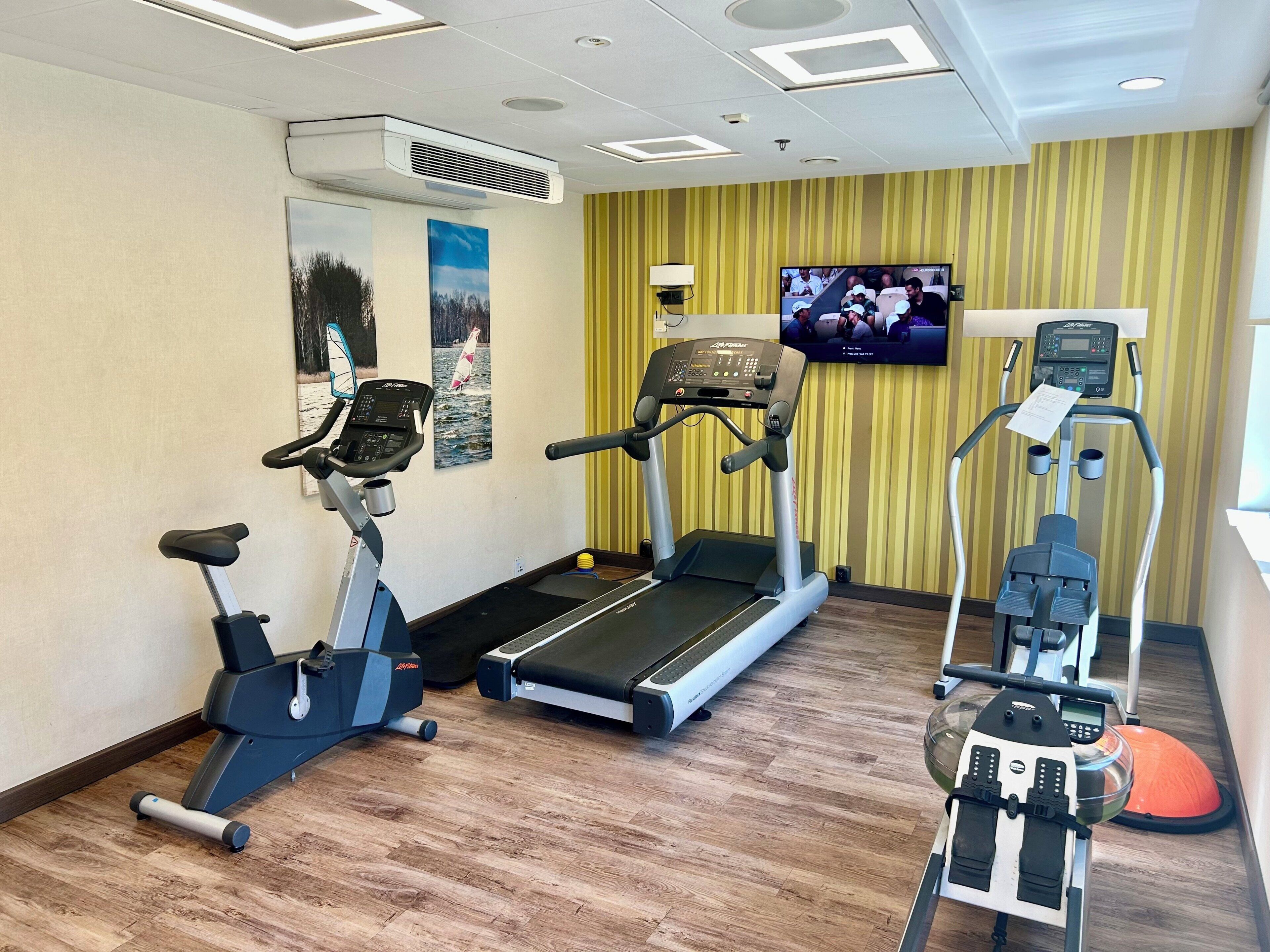 A gym with treadmills, an elliptical, and a rowing machine.