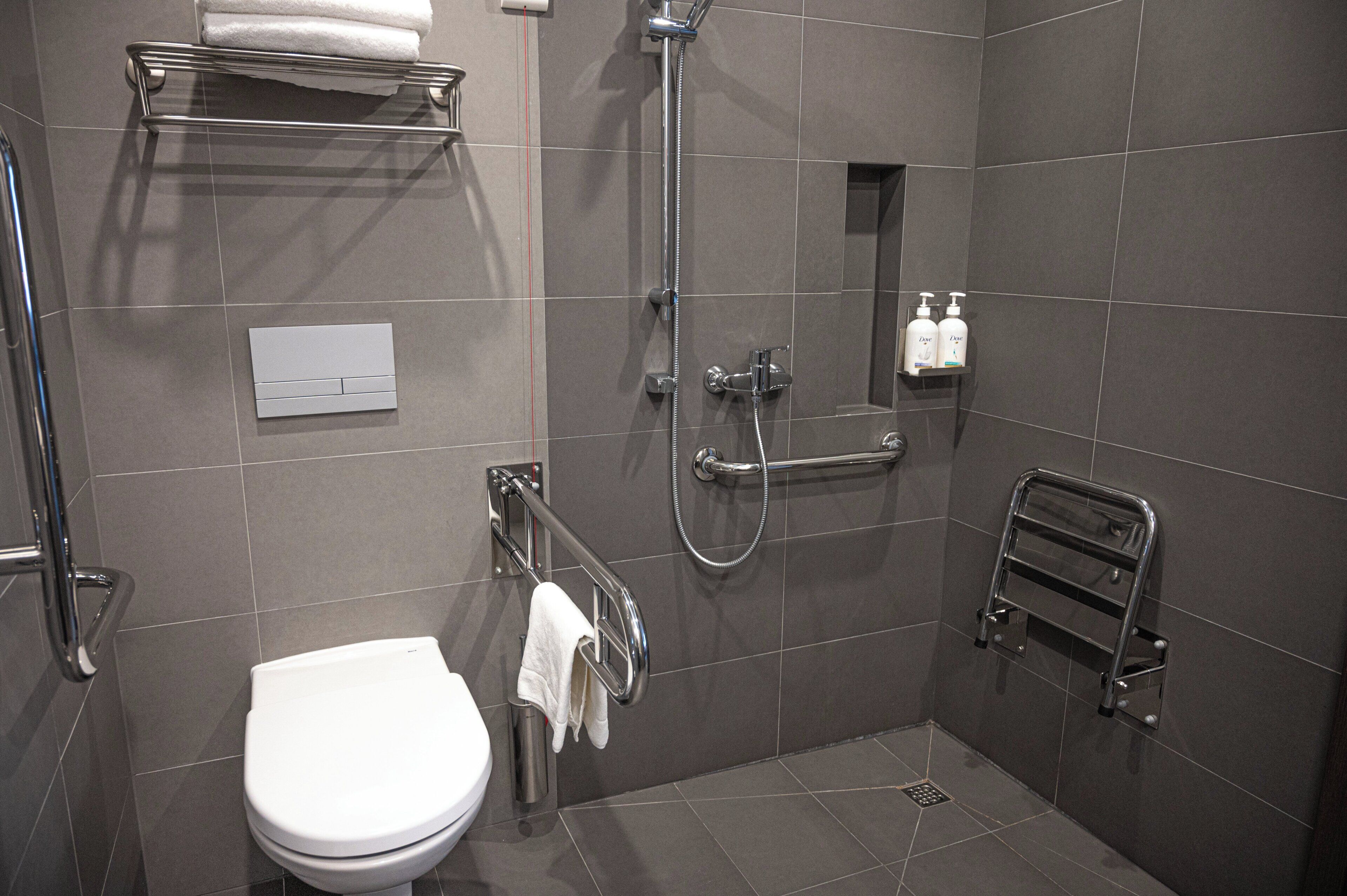 A modern bathroom with a toilet, shower, and towel rack.