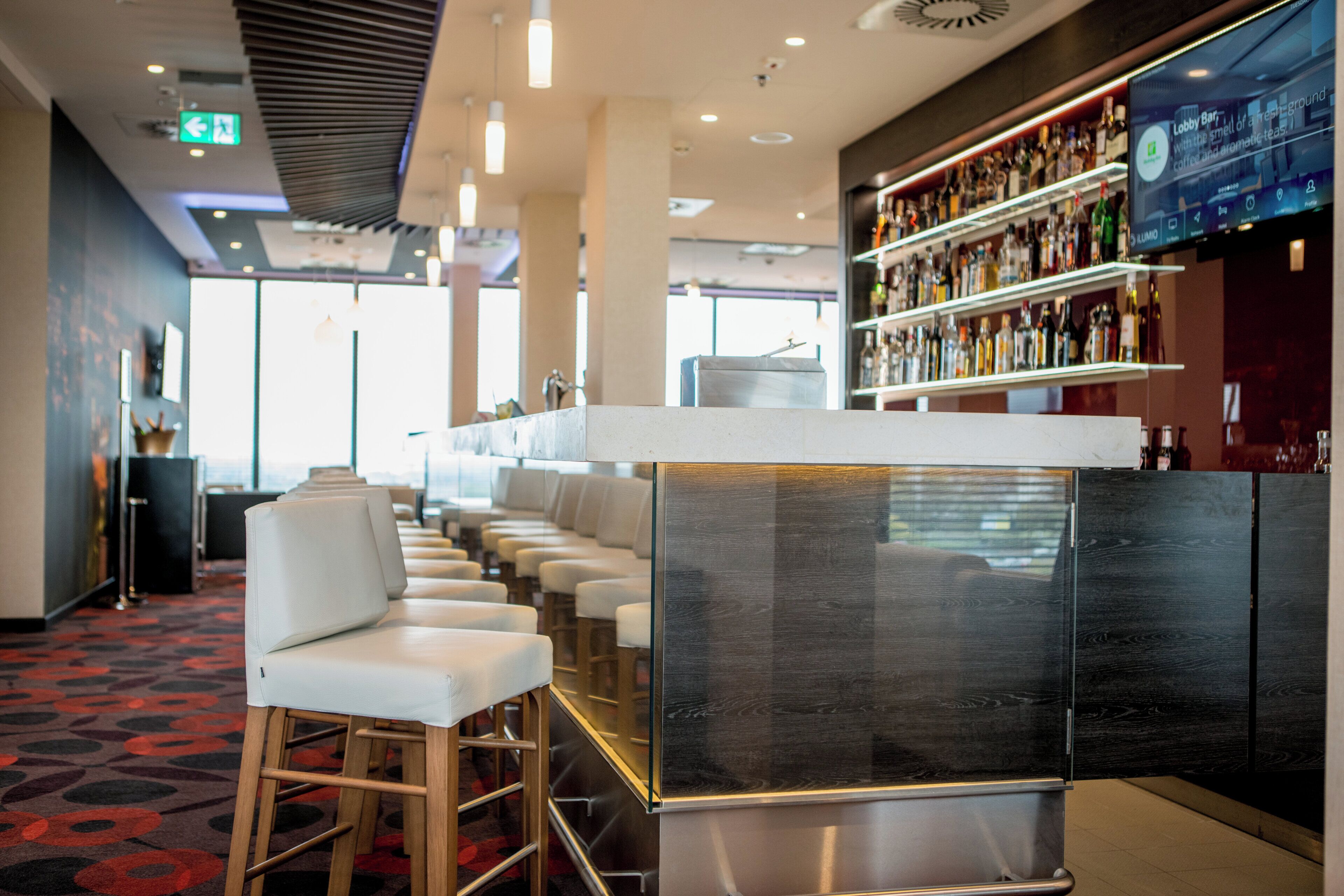 Zona de bar con asientos y una barra que exhibe diferentes botellas.