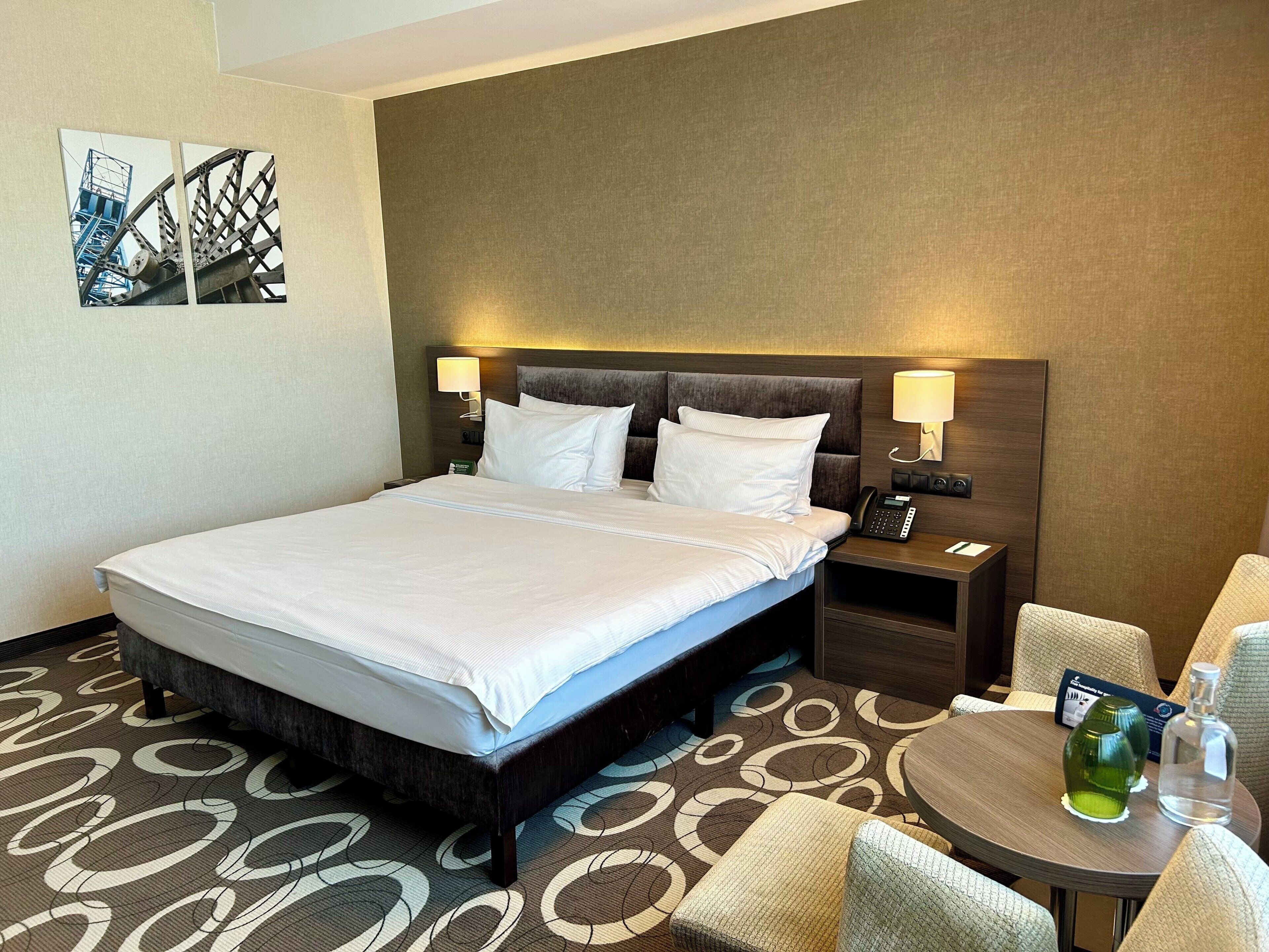 Ein Hotelzimmer mit einem großen Bett, Nachttischen, einem runden Tisch und einem Stuhl.
