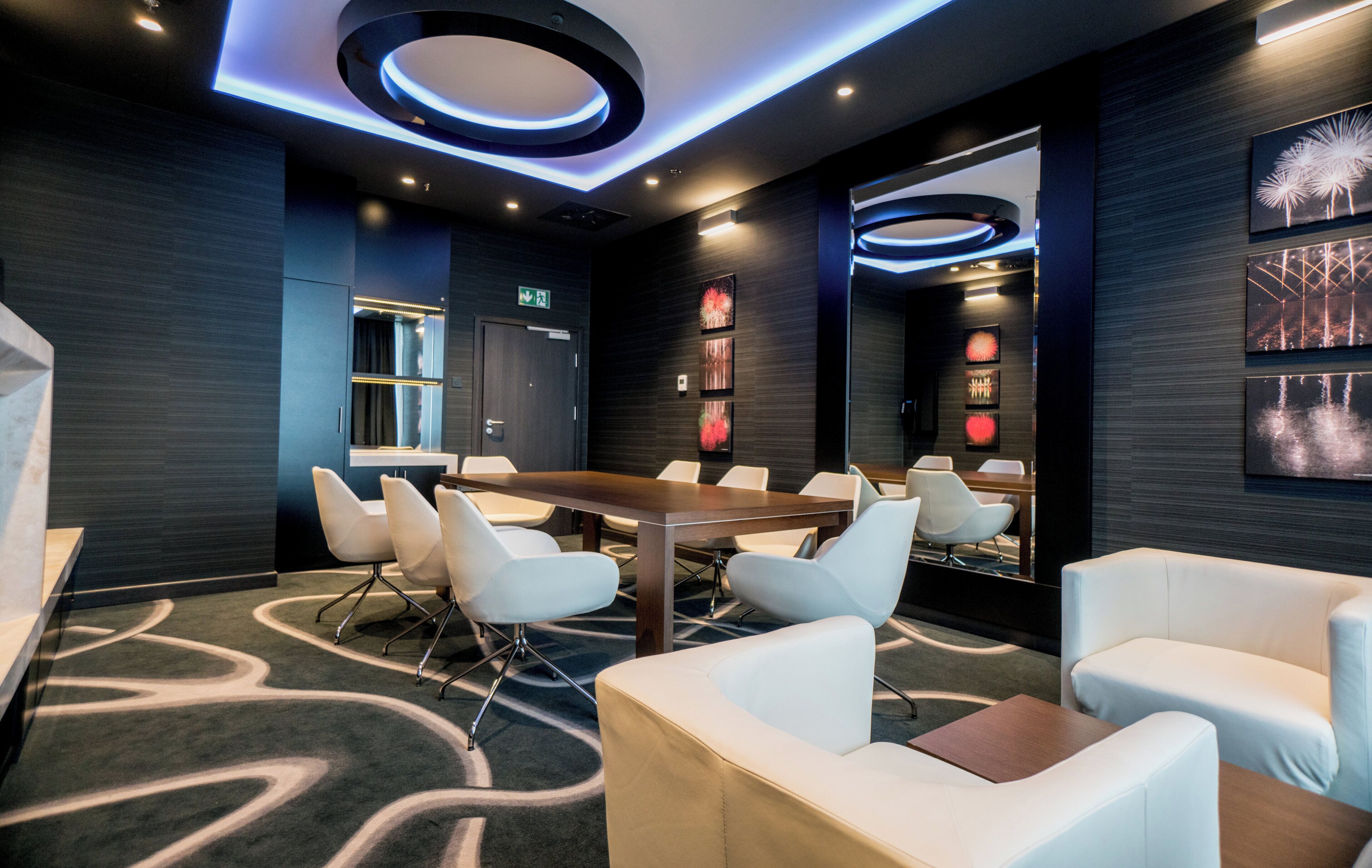 A conference room with a round table, white chairs, and a carpeted floor.