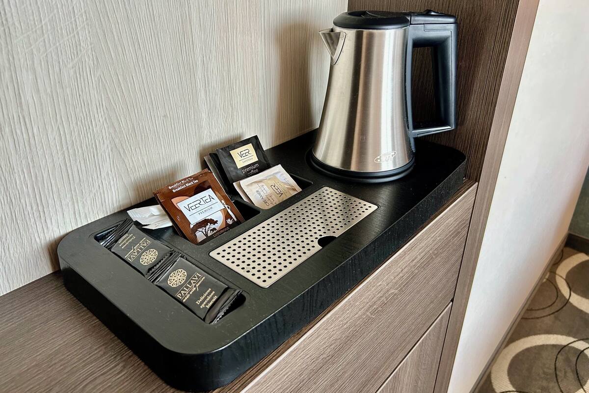 A coffee station with a coffee maker, a tray with coffee pods, and a drip coffee maker.