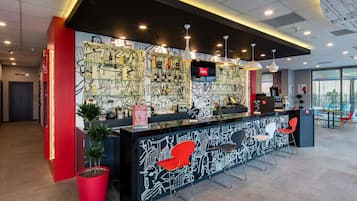 Un área de recepción moderna con un mural en blanco y negro, detalles en rojo y una zona de estar con sillones.