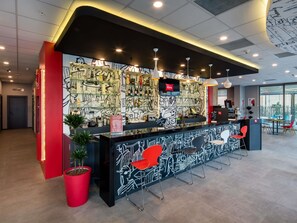A modern reception area with a black and white mural, red accents, and a seating area with chairs. - ibis Istanbul West (Istanbul)