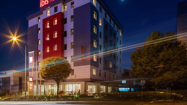 A multi-story hotel with a prominent "ibis HOTEL" sign, large windows, and a well-lit entrance area. - ibis Istanbul West (Istanbul)