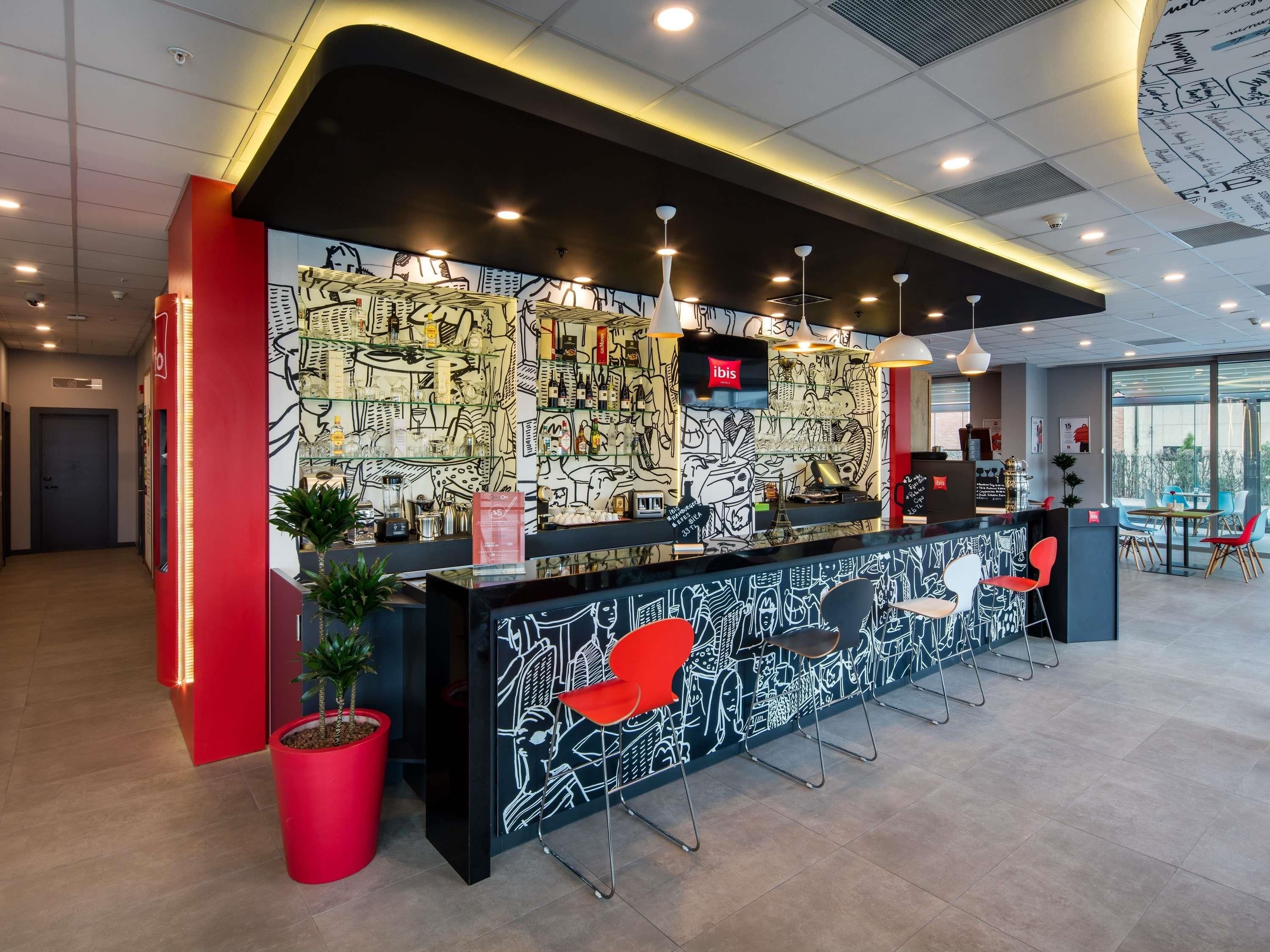 A modern reception area with a black and white mural, red accents, and a seating area with chairs.