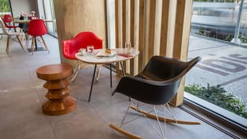 Een modern interieur met een ronde tafel, een schommelstoel en rode stoelen.