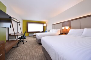 A hotel room with two beds, a desk, a chair, a flat-screen TV, and a window with a view.