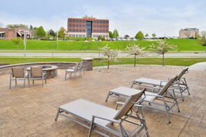 An outdoor patio area with seating and a fire pit, overlooking a parking lot and a building with a sign that reads 'PARK BANK'. - Holiday Inn Express & Suites Madison by IHG (Madison)