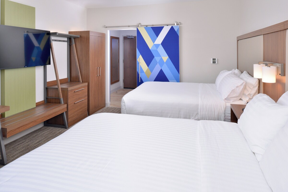 Une chambre d’hôtel avec deux lits, une télévision, un bureau et une armoire.