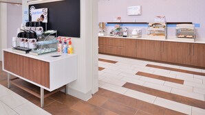 A modern kitchen area with a coffee station, a chalkboard menu, and a buffet counter with food displays. - Holiday Inn Express & Suites Madison by IHG (Madison)