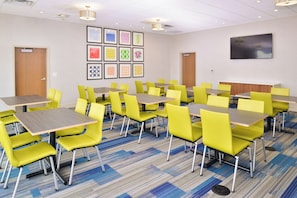 A conference room with tables and chairs, a carpeted floor, and framed artwork on the wall. - Holiday Inn Express & Suites Madison by IHG (Madison)