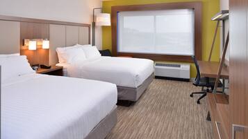 A hotel room with two beds, a desk, a chair, a lamp, and a large window.