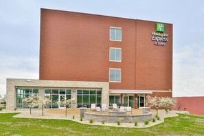 A Holiday Inn Express & Suites building with a brick facade, large windows, and a landscaped outdoor area with seating. - Holiday Inn Express & Suites Madison by IHG (Madison)