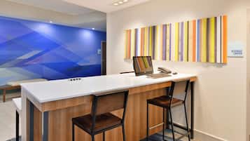 A reception desk with a laptop, two chairs, and a colorful striped wall.
