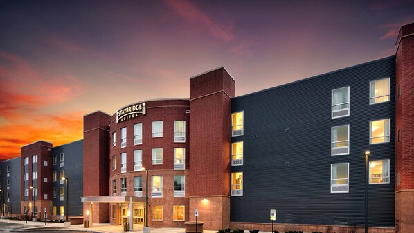 A Staybridge Suites hotel with a brick facade, multiple windows, and a sign indicating accessibility.