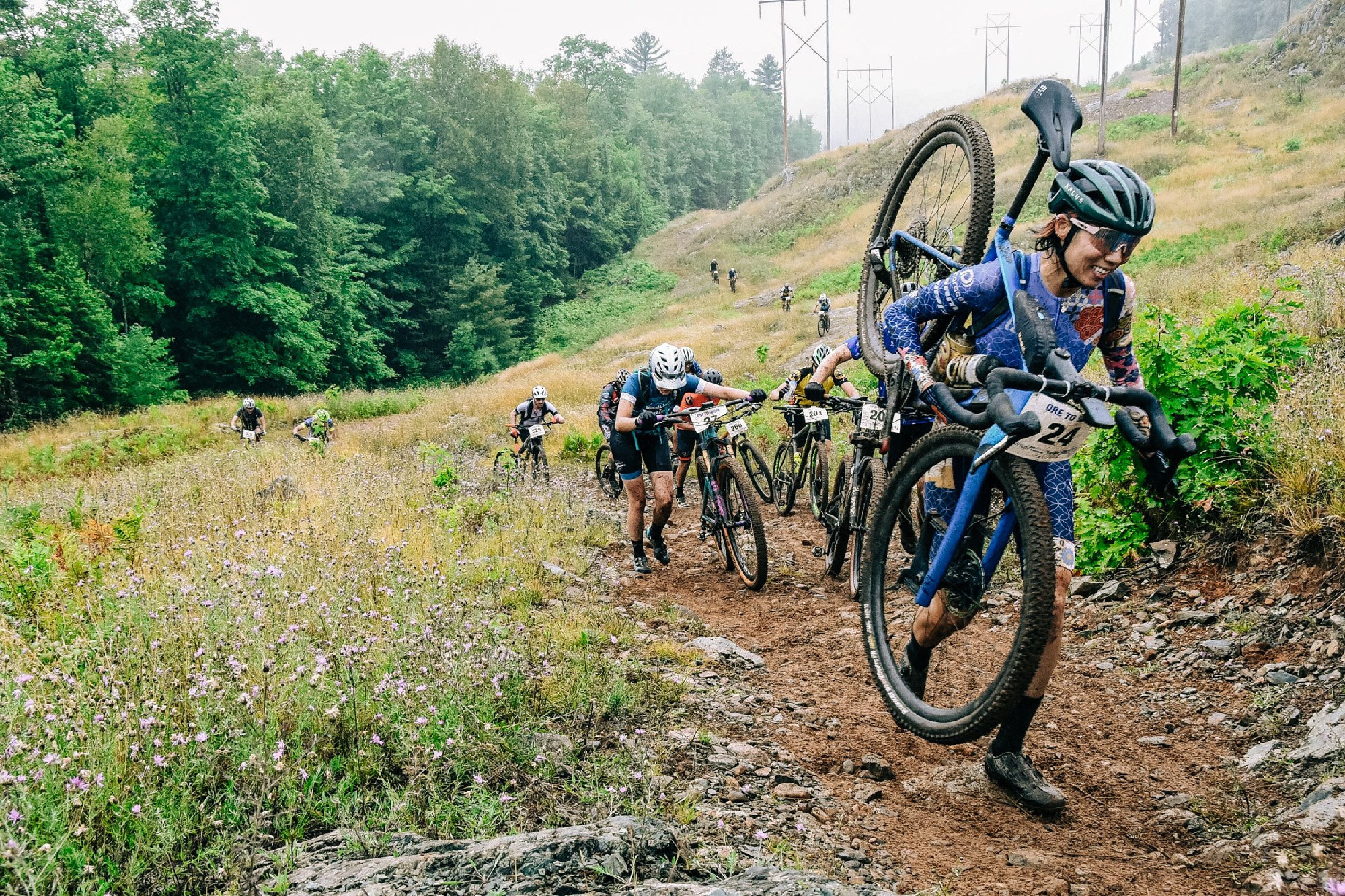 Un grup de ciclistes de muntanya pedalant per un sender de terra envoltat de verdura.