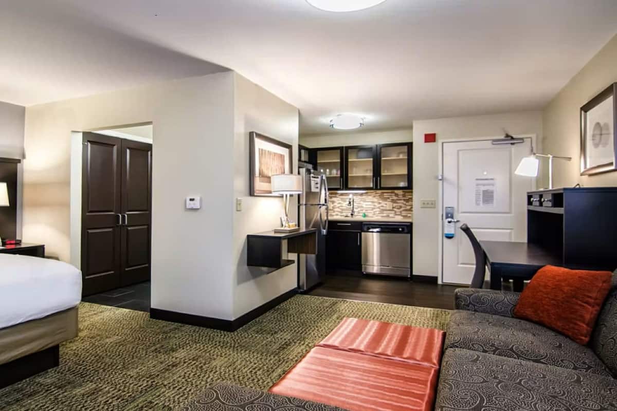 Ein Hotelzimmer mit einem Bett, einer Sitzecke, einer kleinen Küchenzeile und einem separaten Essbereich.
