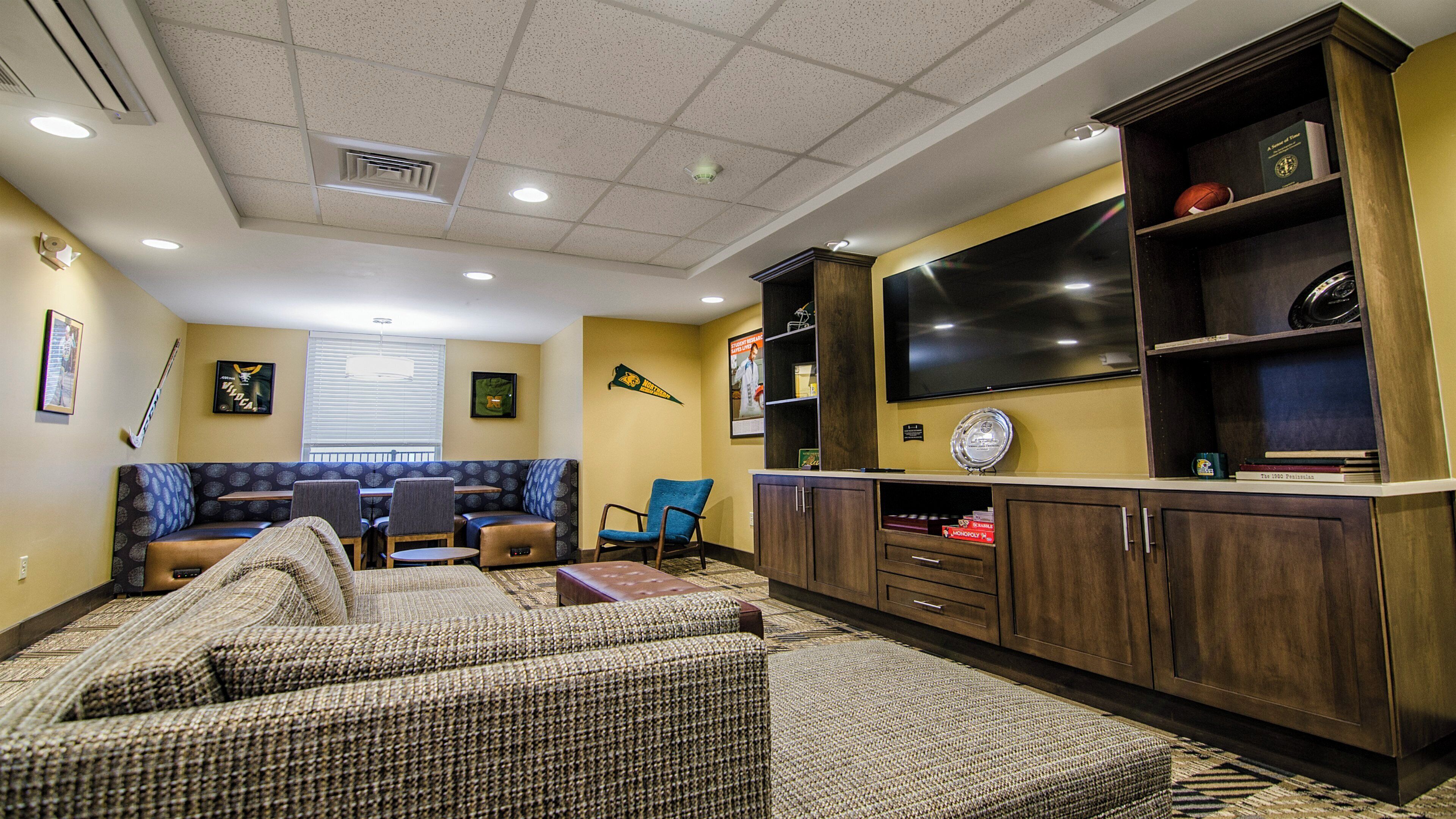 A living room with a sofa, chairs, a television, and a cabinet with various items.
