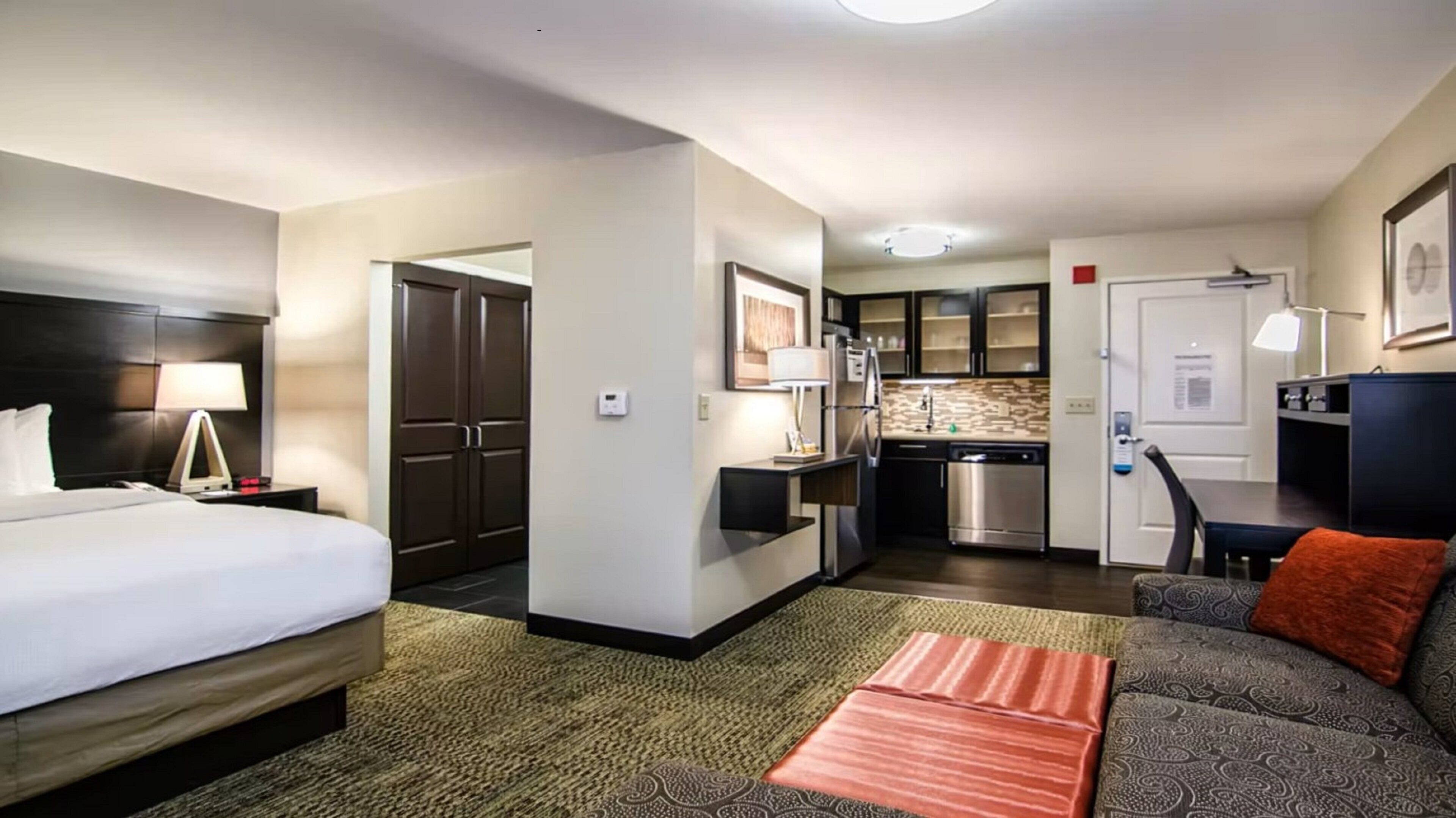 Une chambre d’hôtel comprenant un lit, un canapé, un petit coin cuisine et un espace repas séparé.