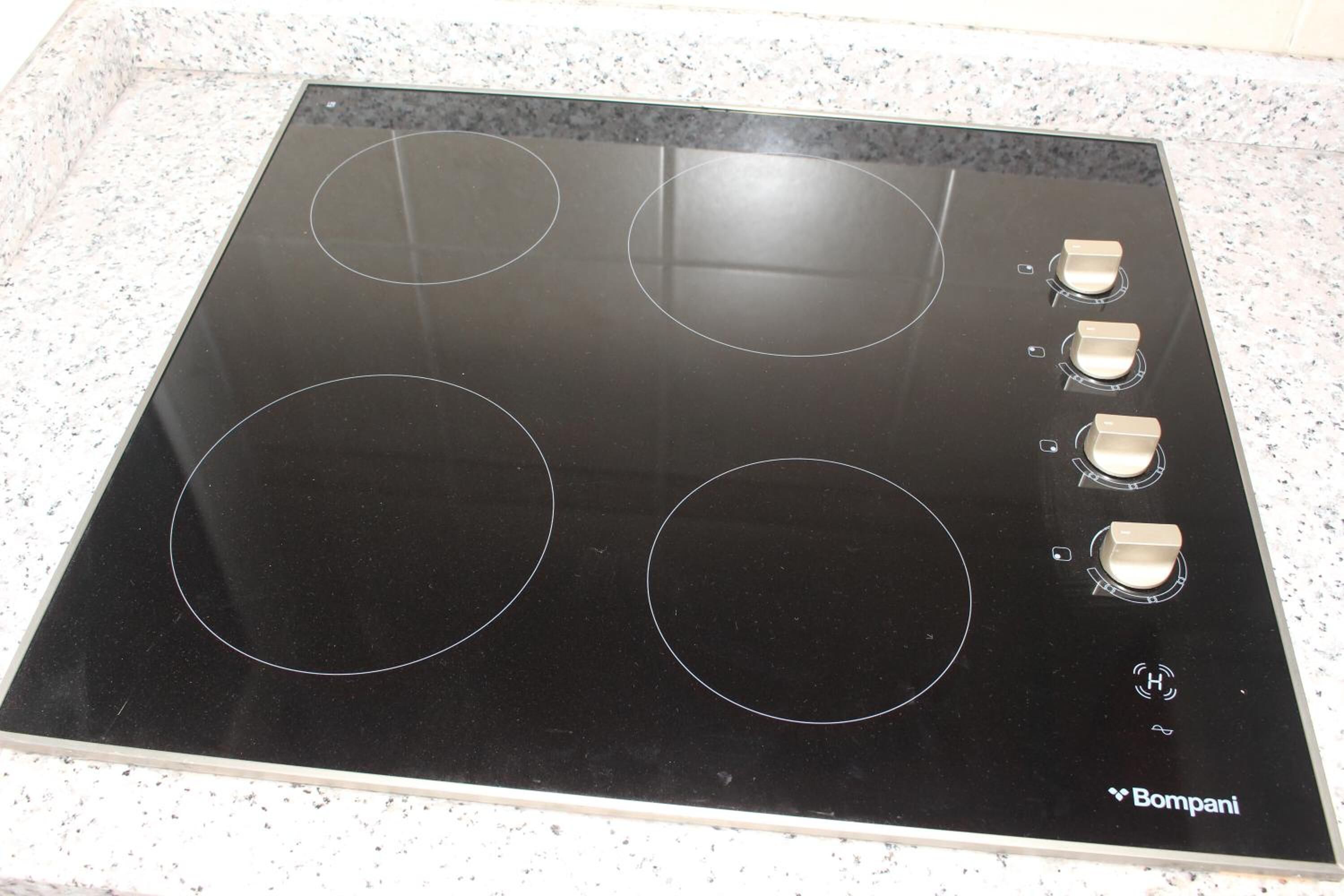 Une plaque de cuisson noire avec quatre brûleurs et un panneau de commande.