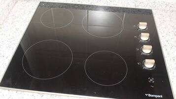 Une plaque de cuisson noire avec quatre brûleurs et un panneau de commande.