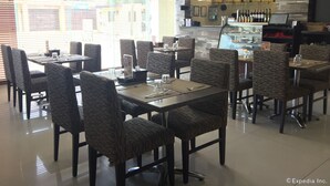 A restaurant with multiple tables and chairs, a counter with a display case, and a television mounted on the wall. - GT Hotel Bacolod (Bacolod)
