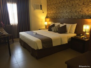 A hotel room with a large bed, two bedside tables with lamps, a desk, and a chair. - GT Hotel Bacolod (Bacolod)