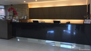 A modern reception desk with a glass partition, framed certificates, and a laptop. - GT Hotel Bacolod (Bacolod)