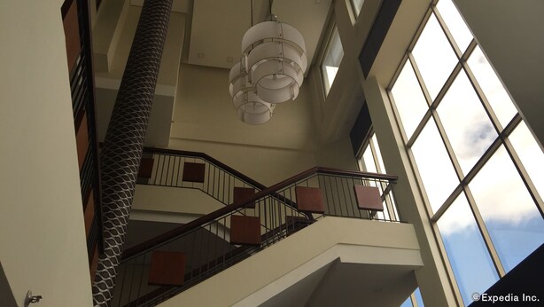 A high-ceilinged interior with a staircase, large windows, and a hanging light fixture. - GT Hotel Bacolod (Bacolod)