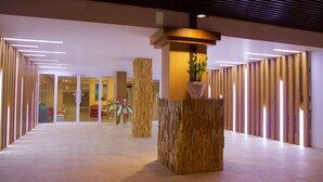 Un hall d’entrée moderne avec un comptoir d’accueil, des panneaux de bois et une plante en pot.