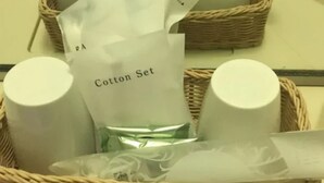Una cesta de mimbre con un juego de algodón, un recipiente cilíndrico y una pequeña bolsa de plástico.