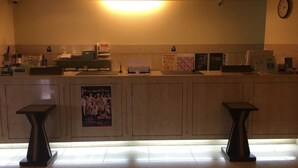 Zona de recepción con mostrador, dos taburetes, un reloj y varios objetos sobre el mostrador.