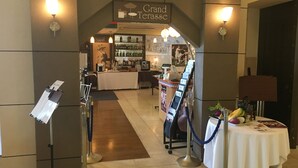Un hall de hotel con mostrador de recepción, zona de bar y área de descanso con mesa dispuesta para una comida.