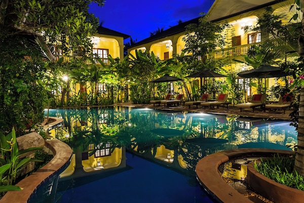 Una piscina al aire libre, sombrillas, sillones reclinables de piscina