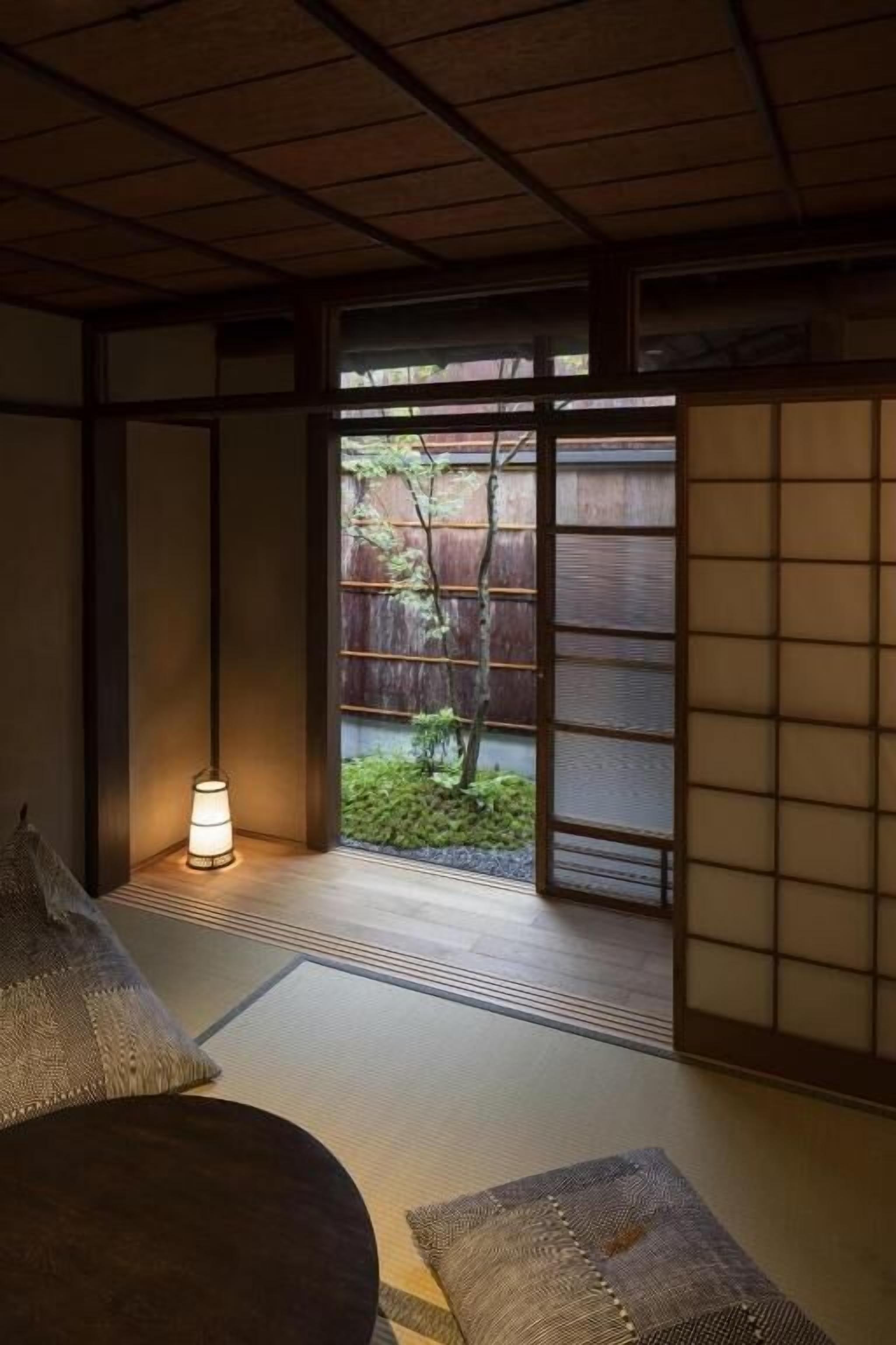 Una habitación japonesa tradicional con suelo de tatami, una mesa baja y un puertas correderas que dan a un jardín.