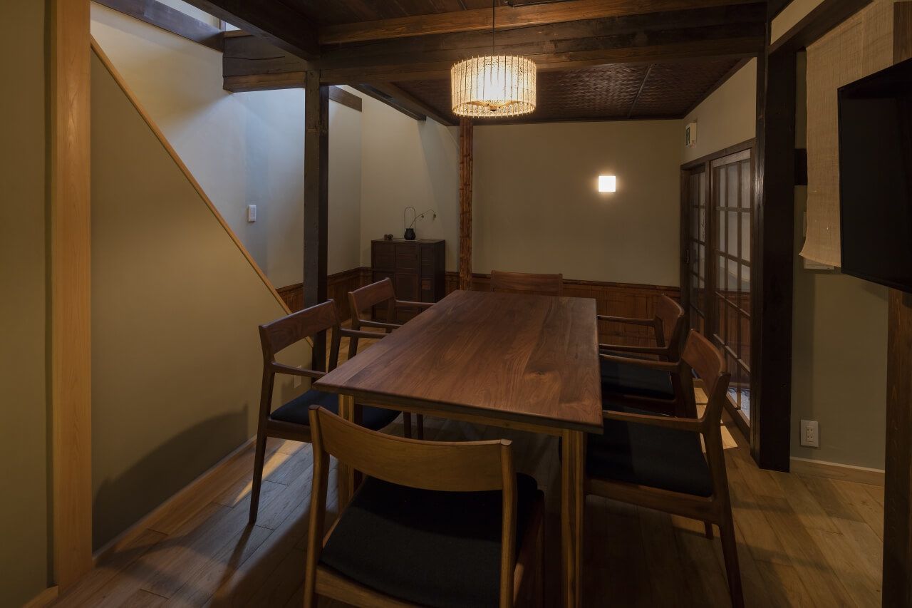 A dining area with a wooden table and chairs, a chandelier, and a traditional sliding door.