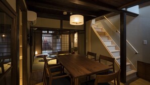 Ett traditionellt japanskt rum med ett matbord, stolar och en trappa, allt tillverkat av trä.