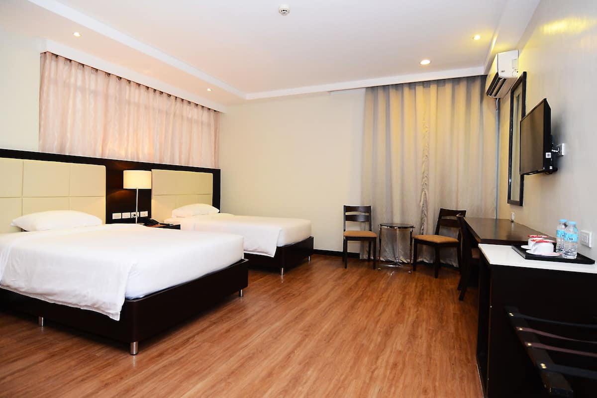 A hotel room with two beds, a desk, a chair, a TV, and a minibar.