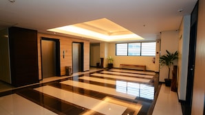 Eine geräumige Lobby mit Schachbrettmuster auf dem Boden, einer zentralen Bank und einem Oberlicht.